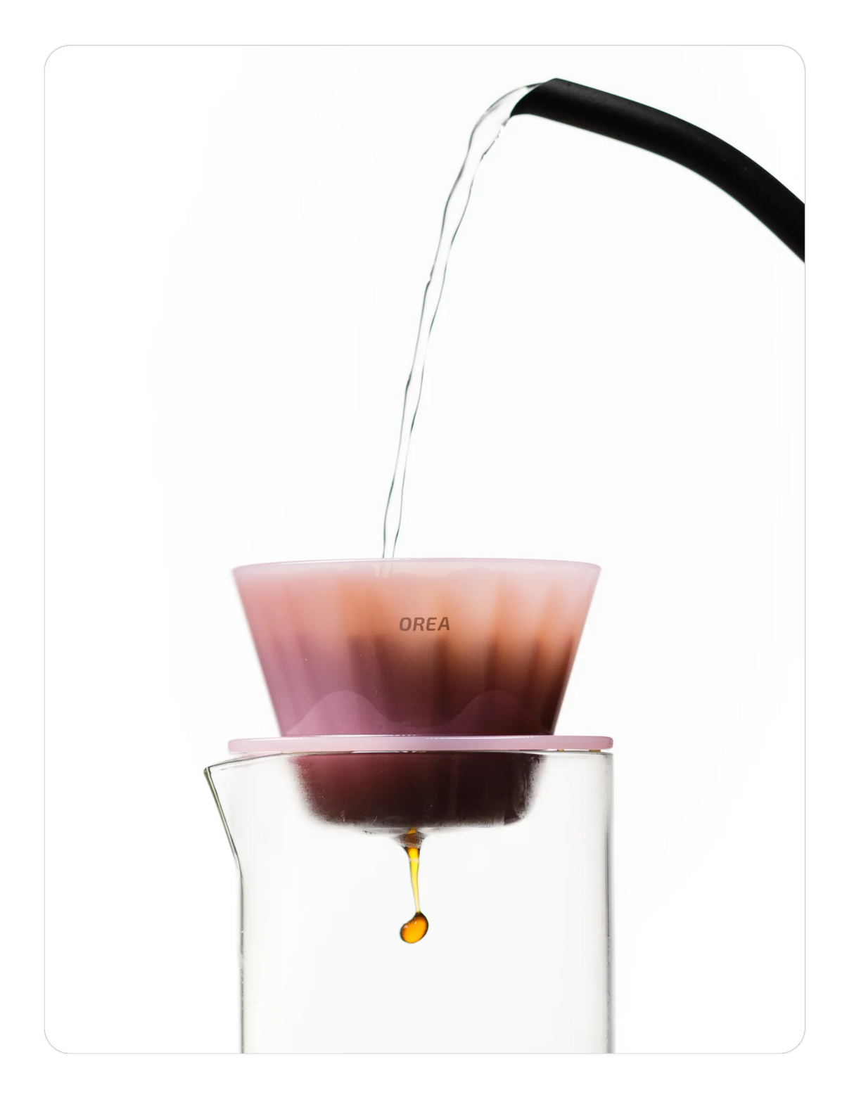 Creamy pink OREA 01 brewer being used to brew coffee into a glass.