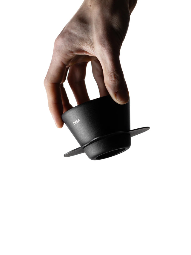 Hand holding a OREA 01 Obsidian coated steel brewer against a white background
