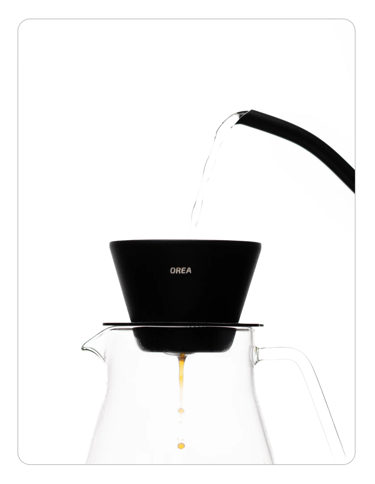 Coffee brewing setup with a OREA 01 Obsidian coated steel brewer and clear glass carafe on a white background