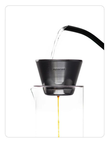 OREA 01 raw steel coffee dripper being used to brew coffee into a glass vessel on a white background